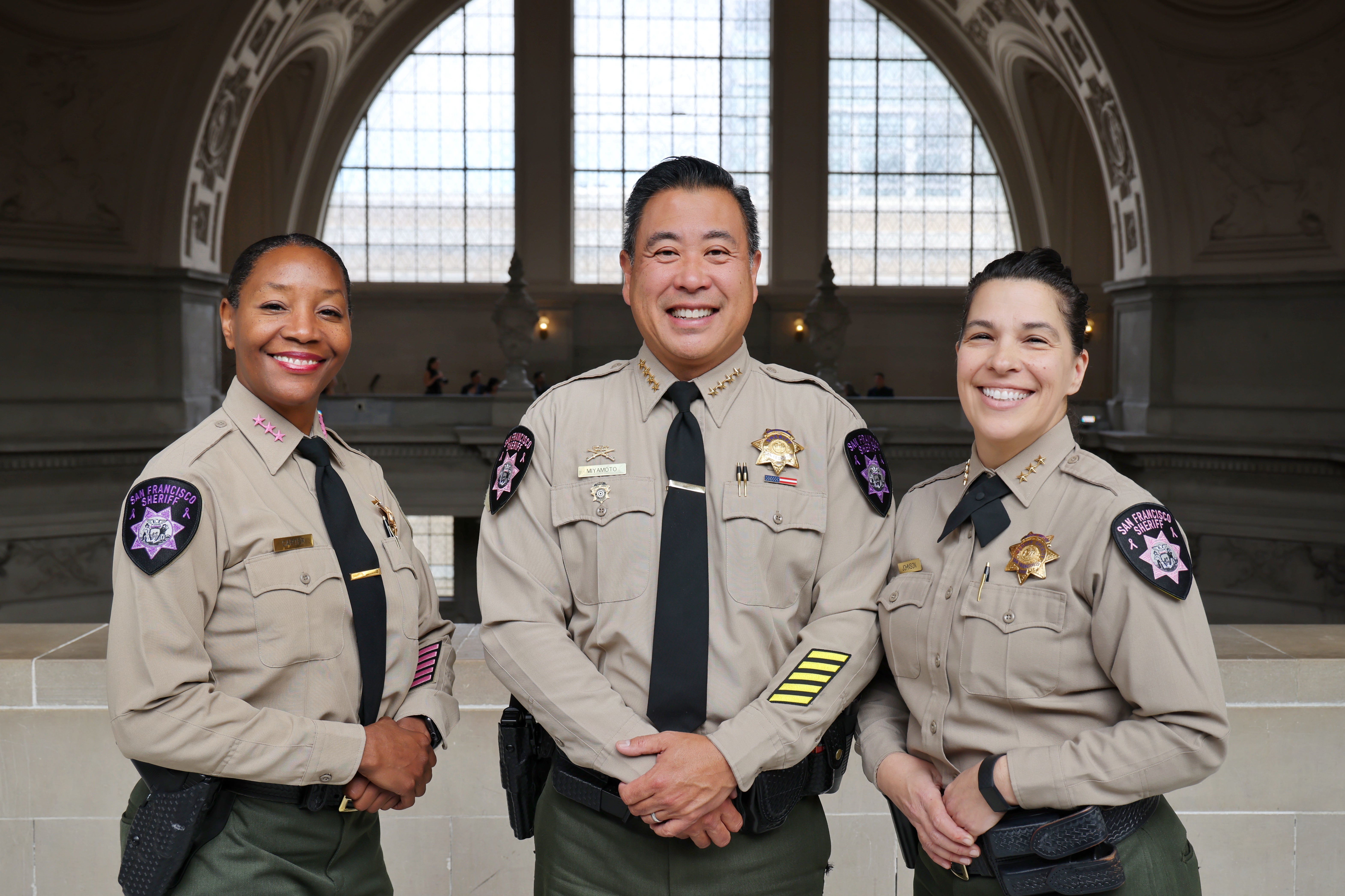 Sheriff Paul Miyamoto (center) is flanked by Assistant Sheriff Tanzanika Carter (left) and Undersheriff Katherine Johnson (right) wearing Breast Cancer and Domestic Violence Awareness Month patches. 